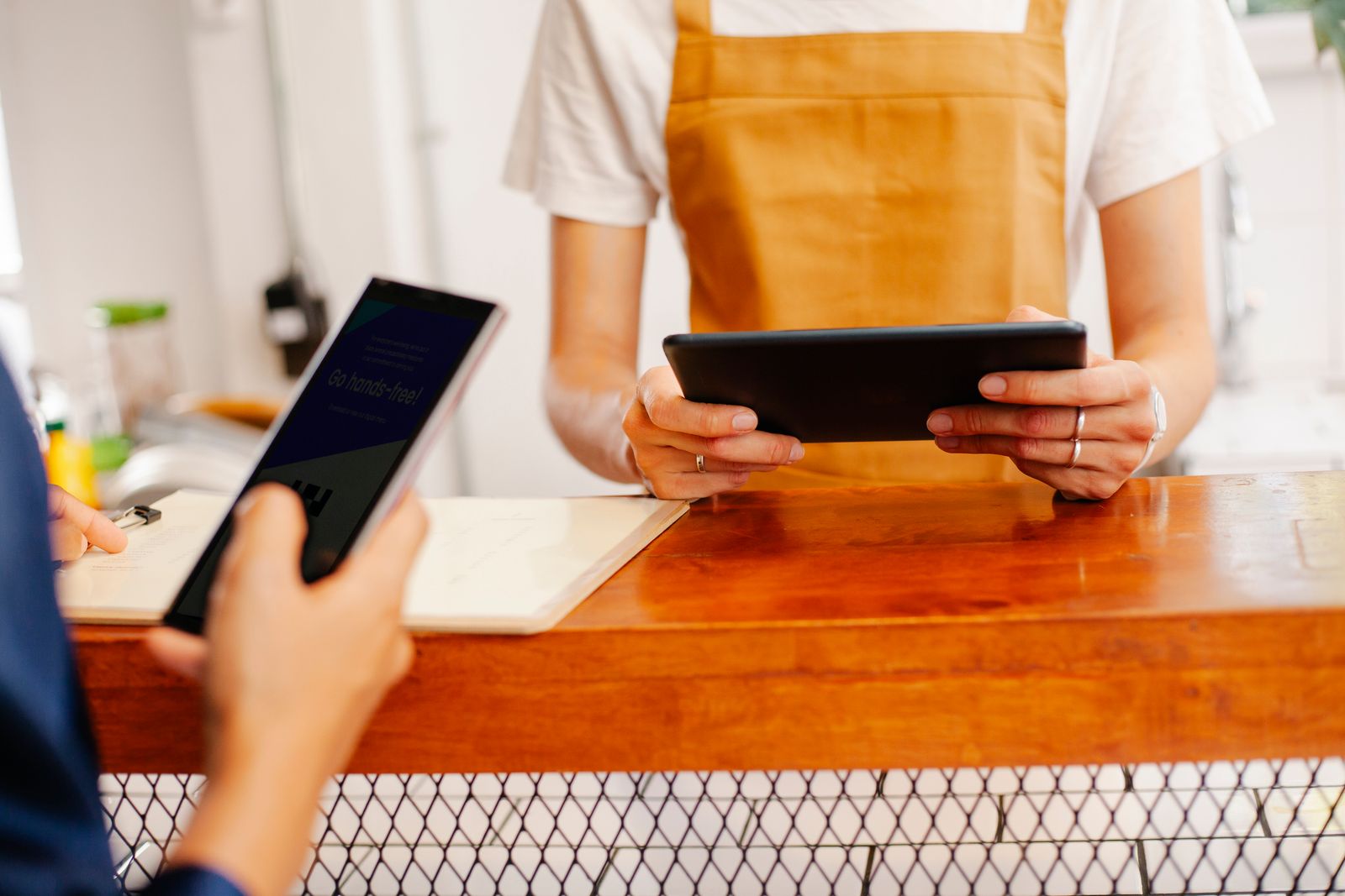 Cafe colleagues using a tablet and phone at the counter