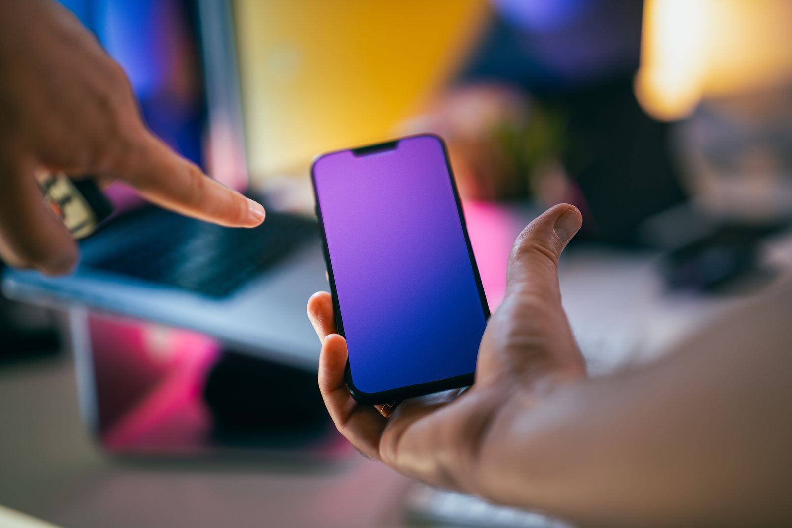 Hands discussing a mobile phone prototype with a gradient screen